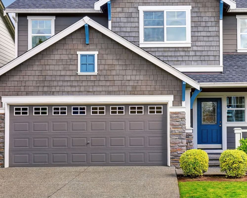 Modern gray house exterior with stone accents and a stylish garage door.